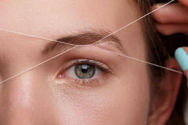 Client showcasing smooth eyebrows after threading, emphasizing natural beauty