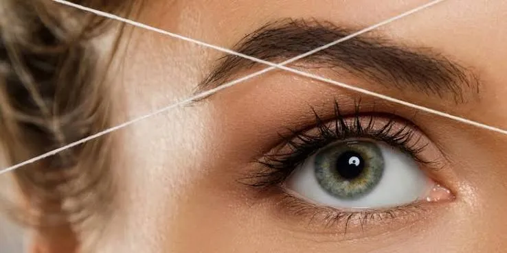 a bright, modern NY Brow & Threading Salon interior on nassau street, showcasing a satisfied client admiring their perfectly shaped eyebrows in a sleek, well-lit salon environment, with a friendly stylist presenting a personalized consultation.