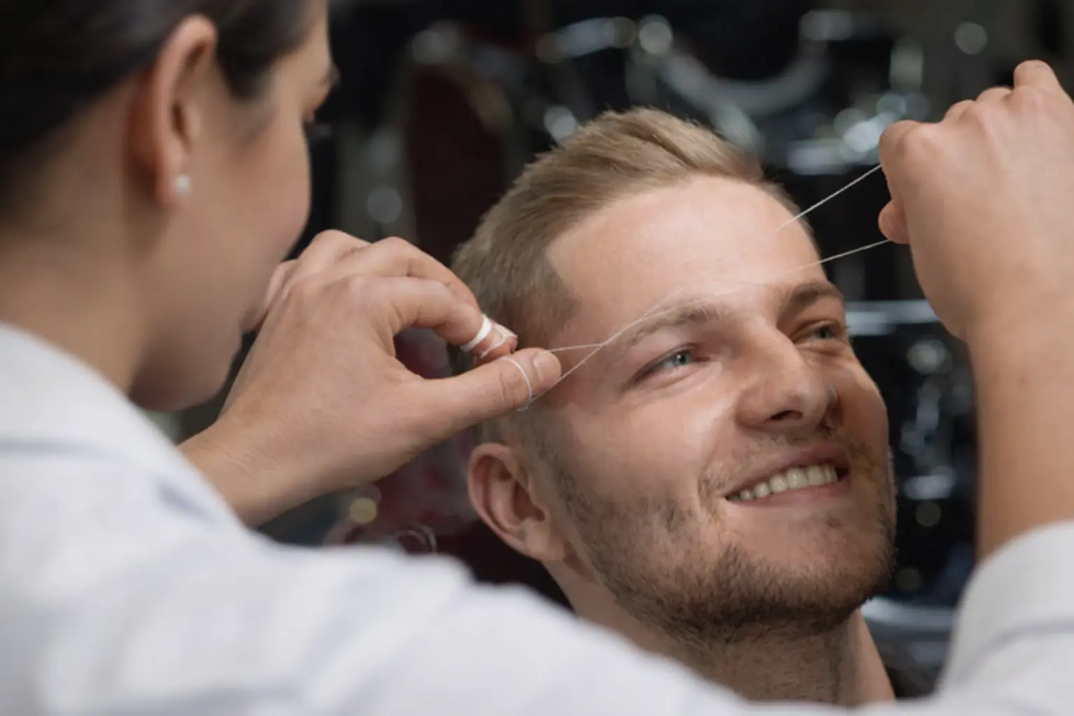 Close-up of a man with well-groomed facial hair and styled eyebrows, showcasing the results of professional waxing and grooming services in a modern salon setting